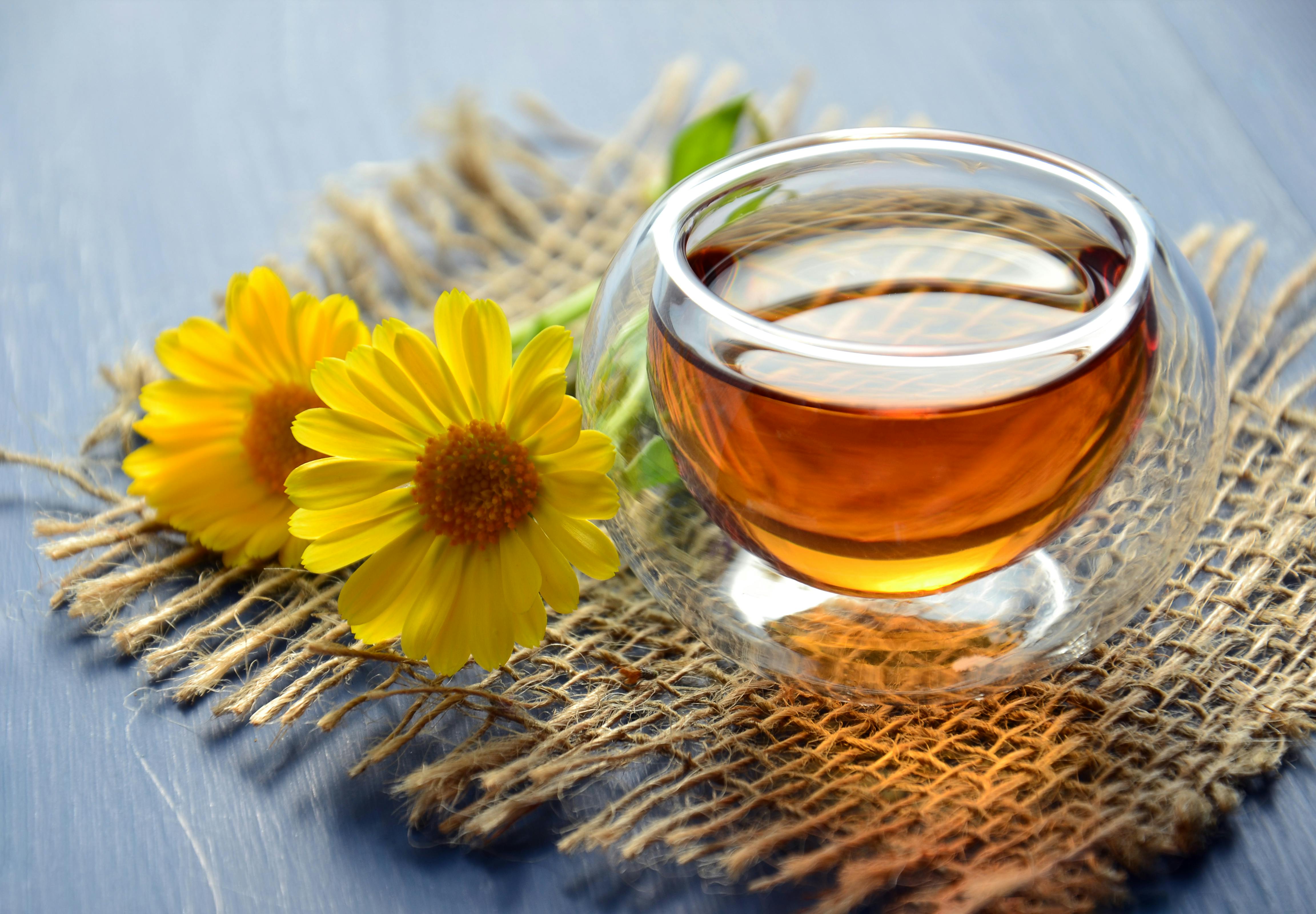 Glass cup of herbal tea with yellow chamomile flowers