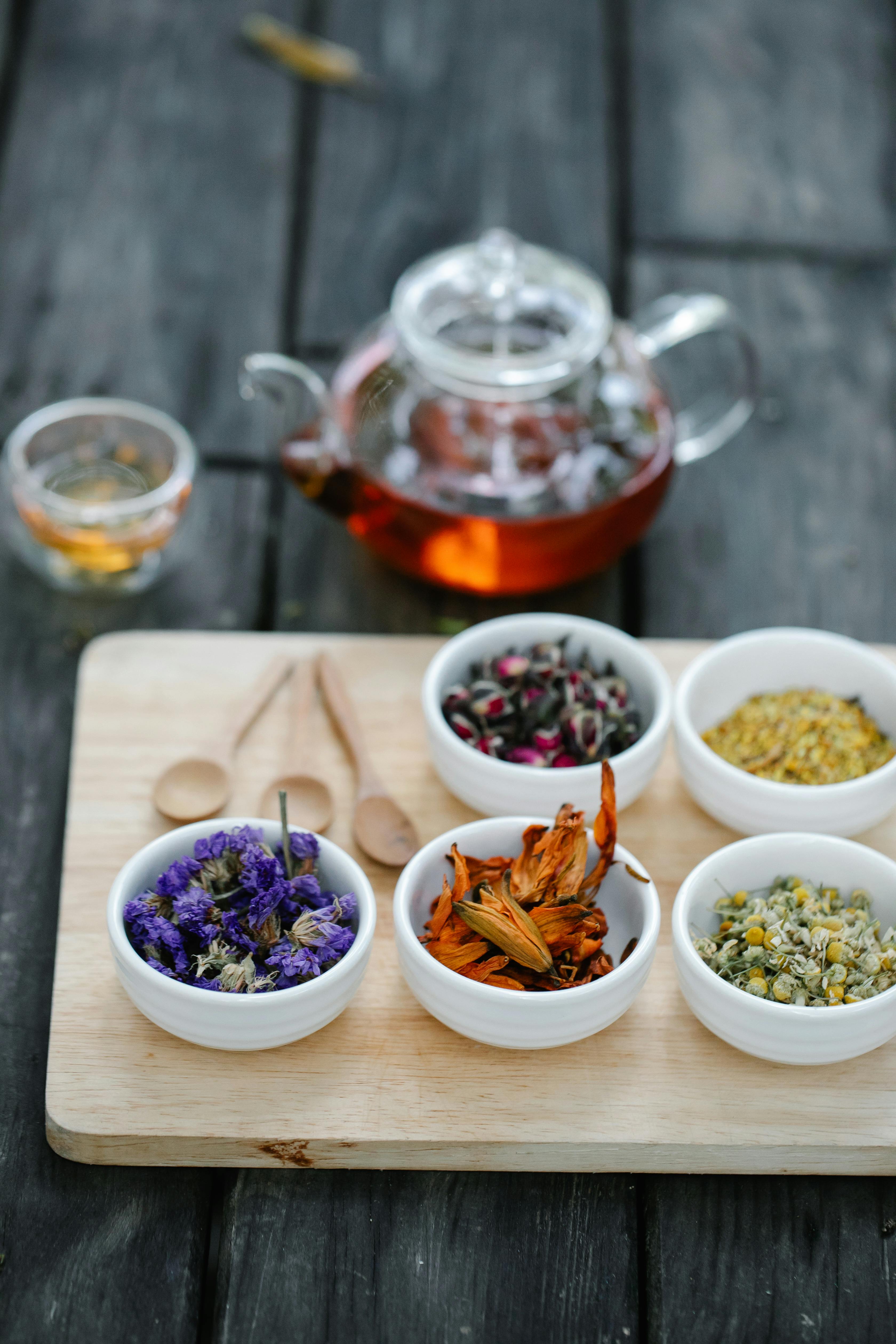 Herbal tea ingredients in white bowls with brewed tea